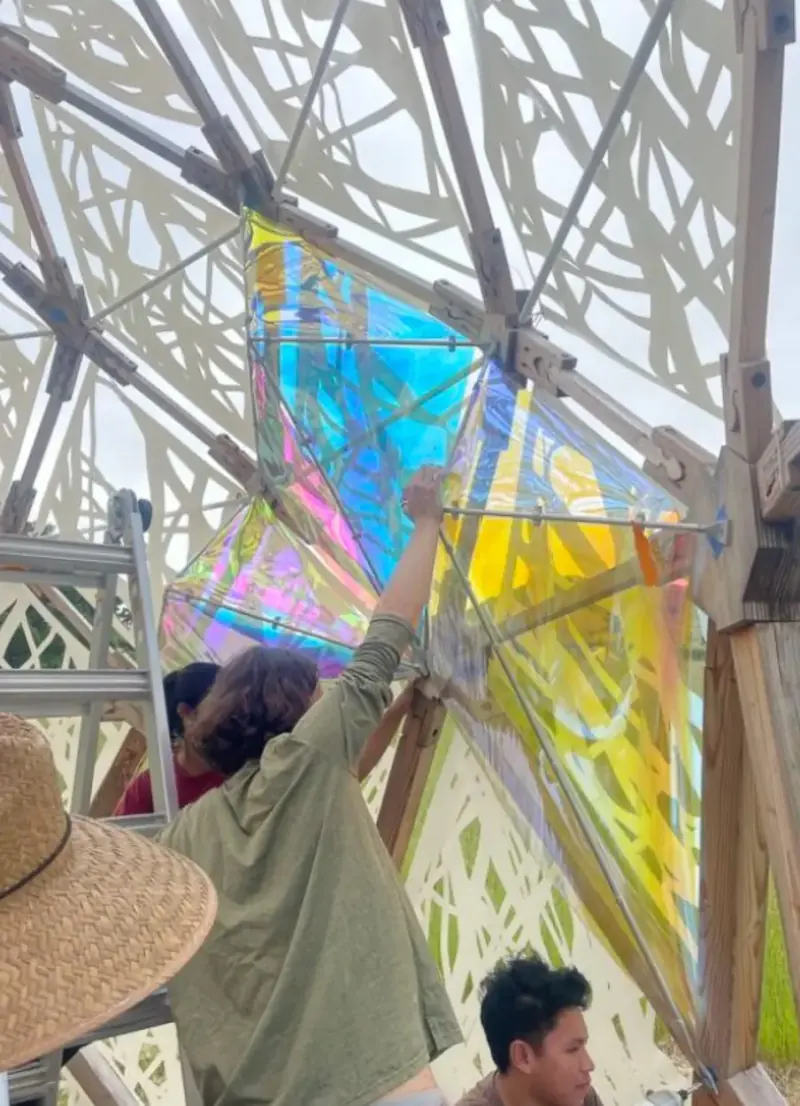A student adding upgrades, including the Biophilic Instrument Pavilion (BIP).