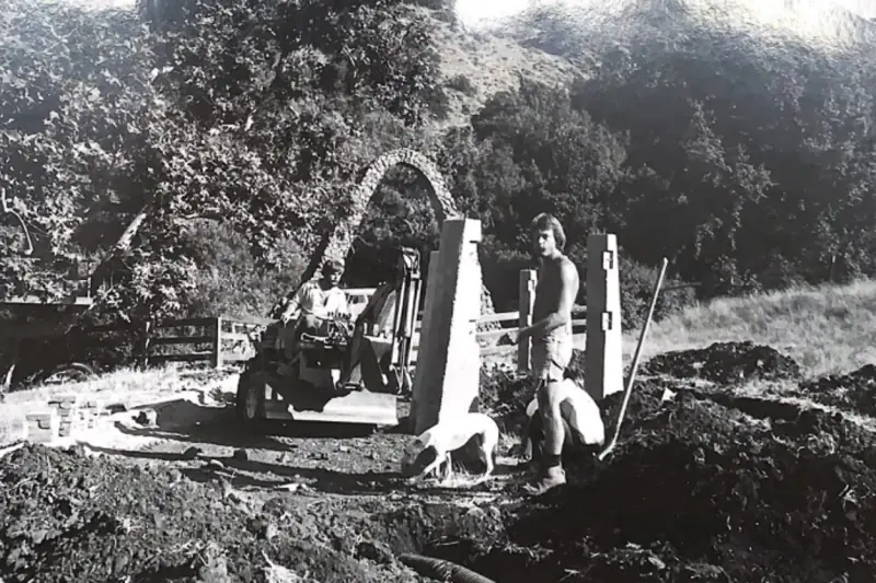 Workers smoothing out the path near missing informational sign.