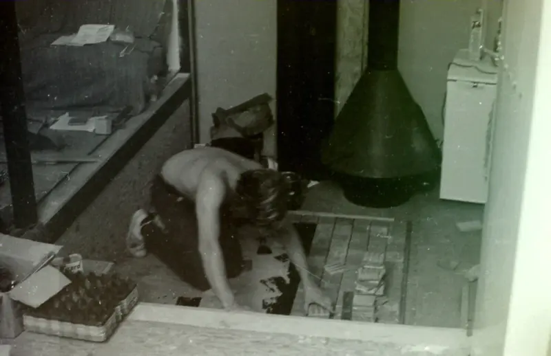 A student tiling the floor near the fireplace.