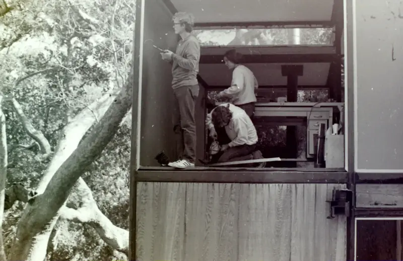 3 students working on the top story of the modular house, a working station.