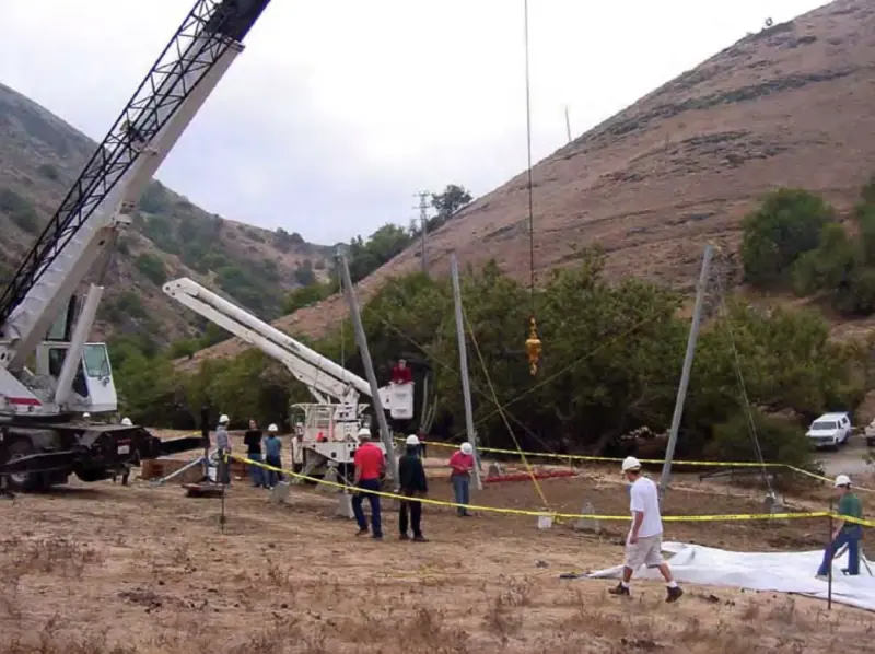 A crane lowering support posts into place during construction.
