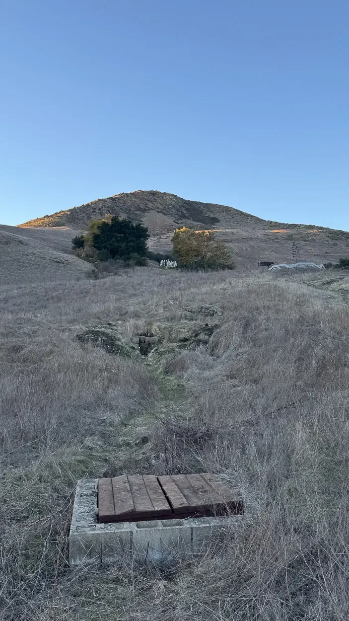 A look into an access point for water infrastructure, that leads straight up to the water tank in the background.